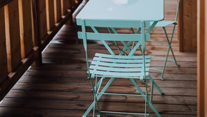 A wooden deck with a table and chairs, overlooking a snowy landscape with buildings in the distance. - Thom's apartment - LES GETS: right in the center and at the foot of the slopes (Les Gets)