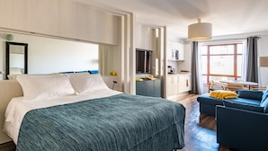 Et moderne hotelværelse med en stor seng, en sofa, et spiseområde og et køkken.
