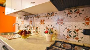 A kitchen with a gas stove, a sink, and a bowl of fruit. - Case Cosi Napoli - Appartamento 12 (Naples)
