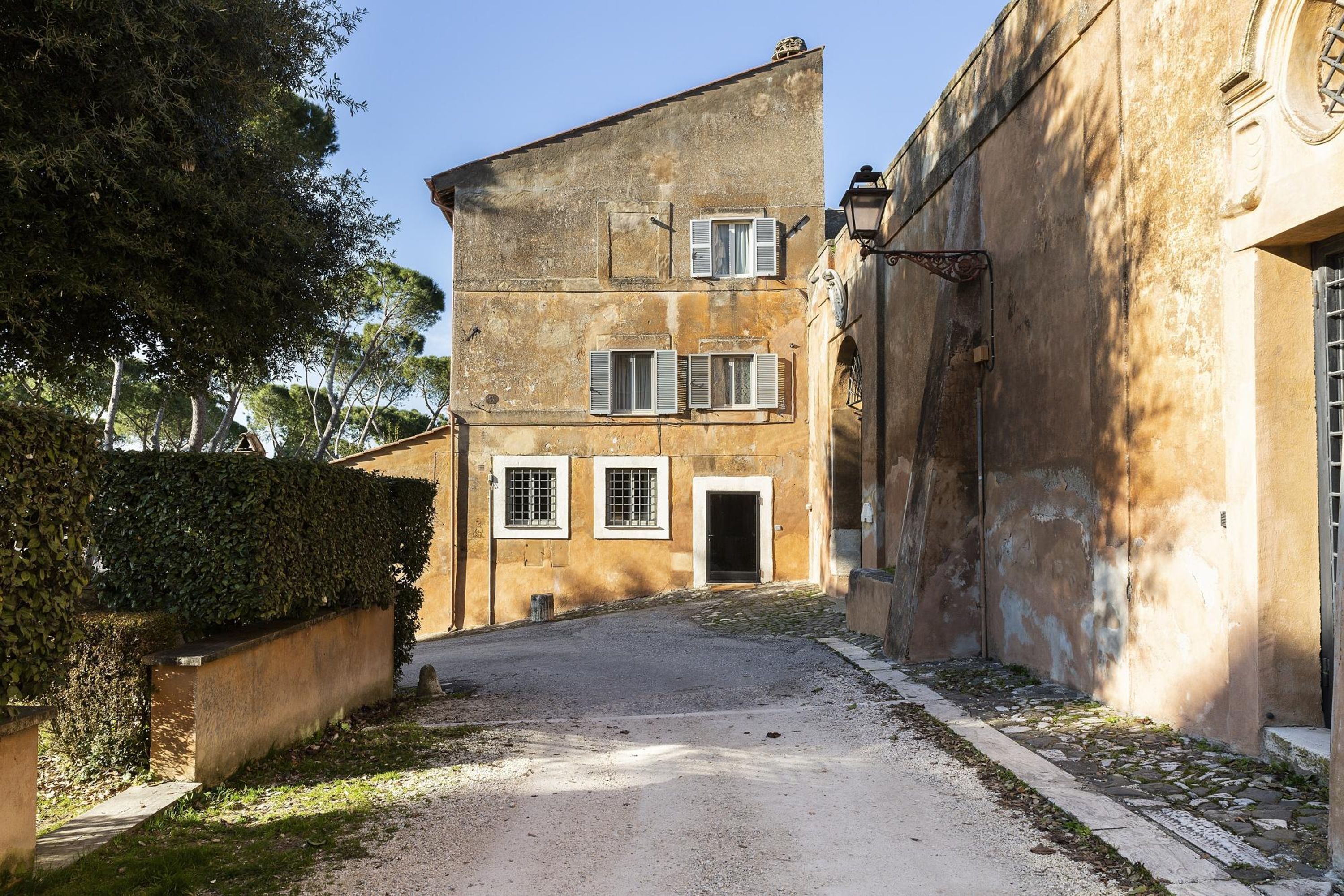 A narrow street with a building featuring a ground floor entrance and upper windows.