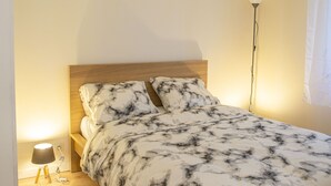 Une chambre à coucher avec un lit, une tête de lit en bois, une lampe de chevet et une lampe sur pied.
