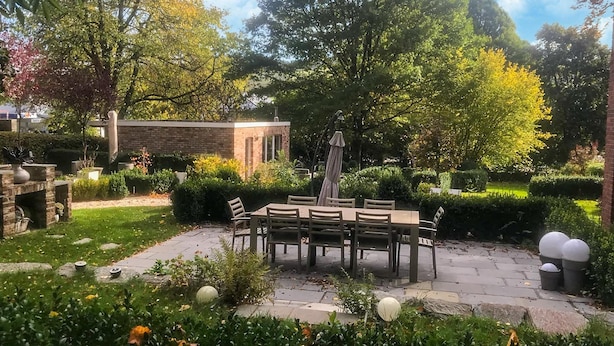A patio with a table and chairs, surrounded by greenery and a brick structure. - Holiday Home With Character in Stavelot (Stavelot)
