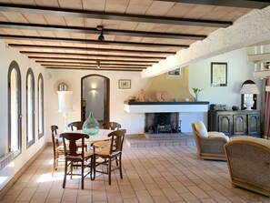 A dining area with a wooden table and chairs, a fireplace, and a ceiling fan. - Maison Avec Jardin, vue Mer, à 500m des Plages (Corbara)