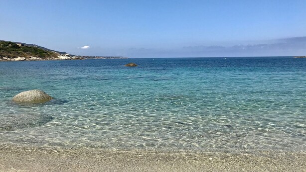 Una vista despejada del litoral, con playa de guijarros y mar tranquilo.
