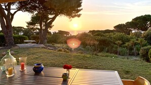 Una mesa con vistas a la puesta de sol, rodeada de árboles y césped.