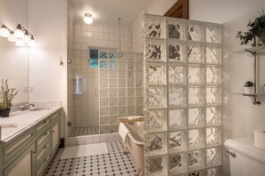 Un baño con cabina de ducha de vidrio, lavamanos y retrete.