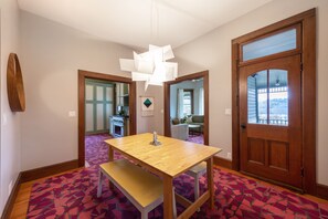 Un comedor con una mesa y banco de madera, una lámpara colgante y vistas a un balcón a través de una puerta.