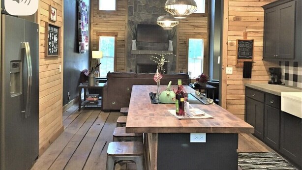 A modern kitchen with wooden walls, a central island, and pendant lighting. - Hawks Ridge Cabin (Saint James)