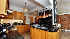 Una cocina moderna con gabinetes de madera, encimeras de granito y ollas colgantes.