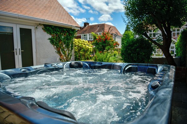 A hot tub with a view of a house and garden in the background. - Just Stay Wales - Highmead House (Swansea)