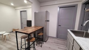 Une cuisine de taille réduite, avec une table en bois et des tabourets de bar, un réfrigérateur et un évier.