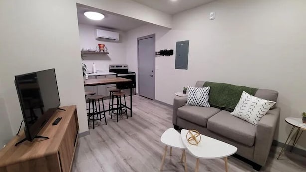 Un espace de vie compact comprenant un coin cuisine, un canapé, une table basse et un téléviseur.