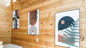 A wooden interior with a staircase and three framed artworks on the wall.