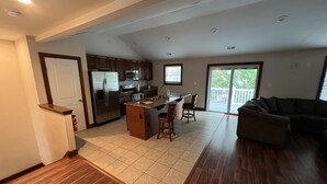 A spacious kitchen with a central island, wooden flooring, and a sliding glass door leading to a balcony. - Luxury Beach Side Home 2 Bedroom Home by RedAwning (Norfolk)