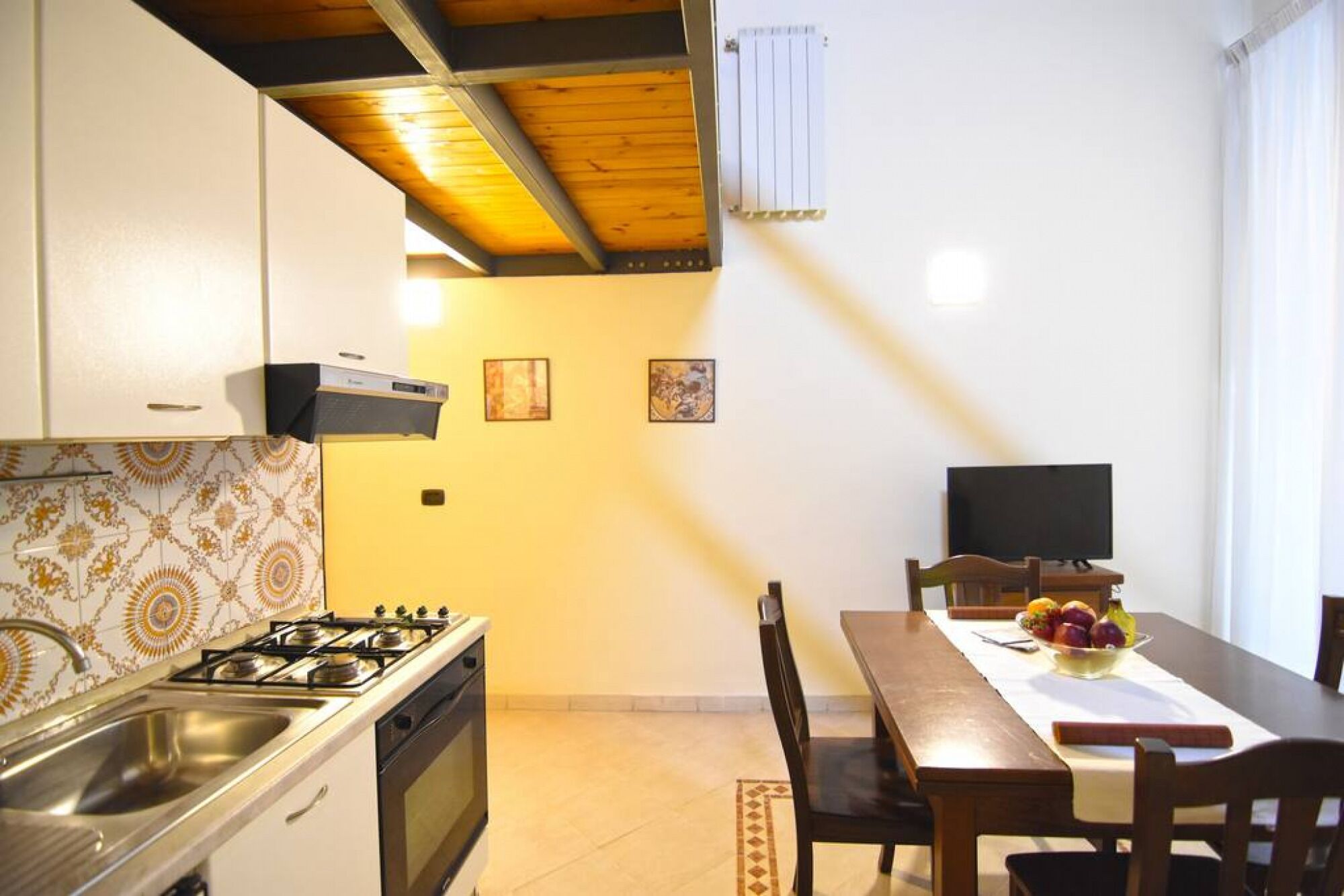 A kitchen with a gas stove, a sink, and a dining area with a table and chairs.