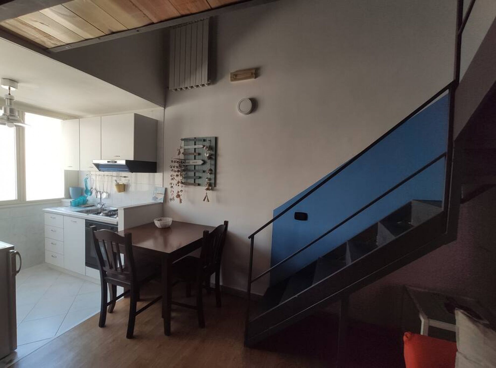 Une cuisine moderne avec un coin repas, un escalier et une vue sur l’espace de vie adjacent.