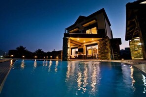 A modern hotel with a pool, large windows, and stone facade.