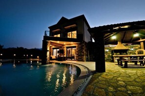 A two-story house with a swimming pool at dusk.
