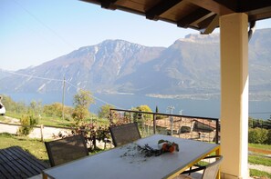 Une terrasse avec une table et des chaises, offrant une vue sur un lac et des montagnes.