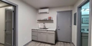 A compact kitchen with a built-in sink, a small countertop, and a grey door. - Bighorn Loft in Downtown Custer, Sleeps 6 (Custer)