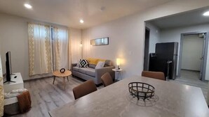 A modern living room with a sofa, a coffee table, and a dining table.