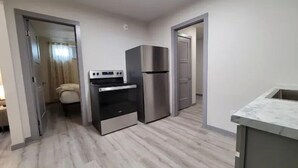 A compact kitchen with a built-in oven, a stainless steel refrigerator, and a marble countertop.