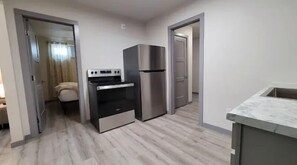 A compact kitchen with a built-in oven, a stainless steel refrigerator, and a marble countertop. - Bighorn Loft in Downtown Custer, Sleeps 6 (Custer)
