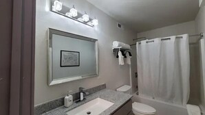 A bathroom with a sink, mirror, and shower curtain.