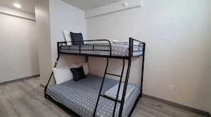 Ein Etagenbett mit gemustertem Matratze und Kissen, ein kleiner Nachttisch und eine schlichte weiße Wand.