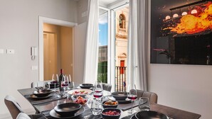 A dining room with a table set for four, a view of a building through an open door, and a modern painting on the wall. - Casa San lio - Casa San Lio (Noto)