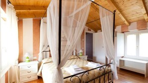 A four-poster bed with white curtains, a bedside table with a lamp, and a window with curtains. - Barchi Resort Apartments Suites Villa Castello - Panoramic Villa Castello (San Felice del Benaco)
