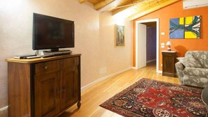 A living room with a TV on a wooden cabinet, a patterned rug, and a couch. - Barchi Resort Apartments Suites Villa Castello - Panoramic Villa Castello (San Felice del Benaco)