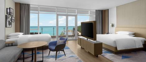 A modern hotel room with a large balcony, a sofa, a chair, a TV, and a bed.