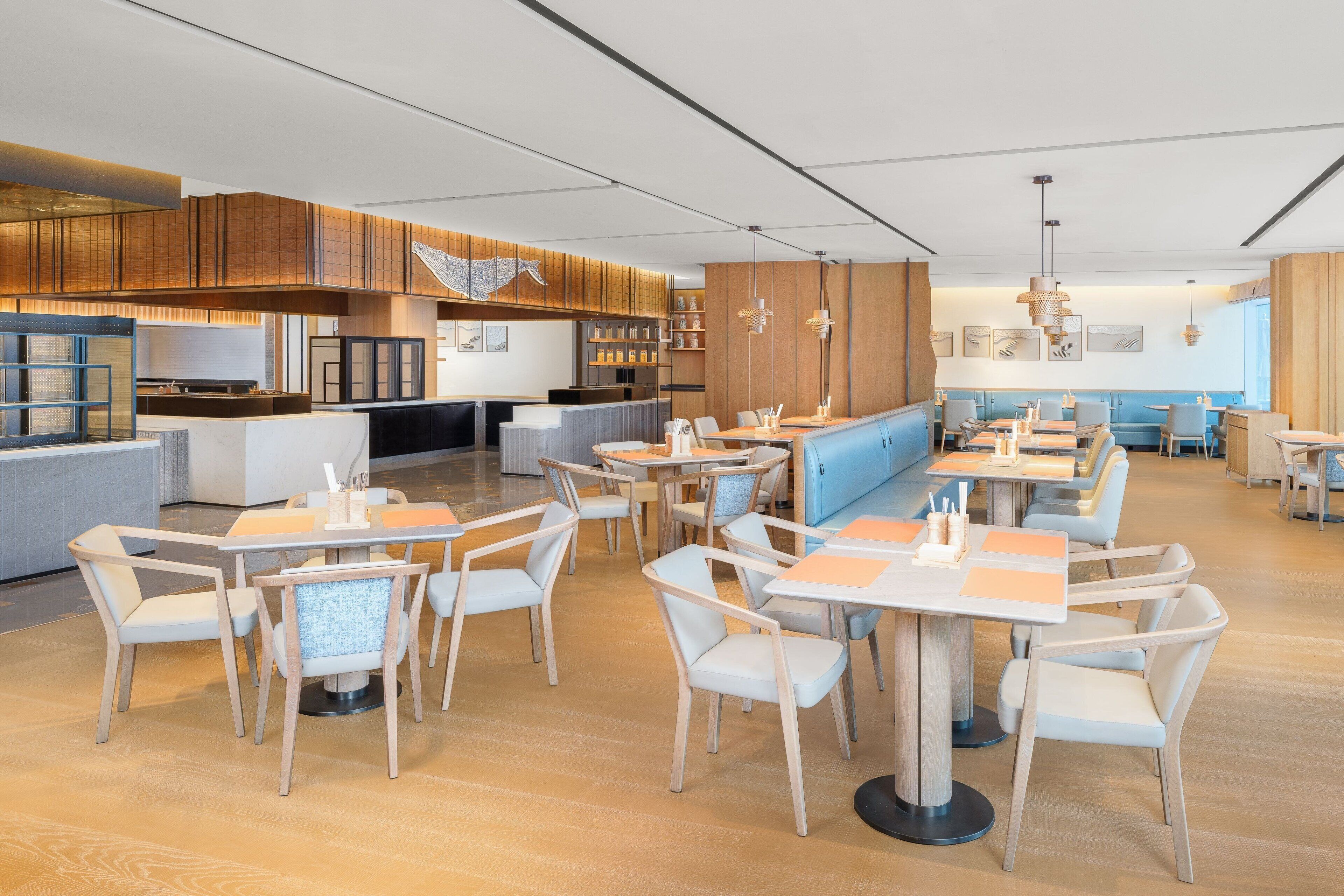 A modern restaurant with wooden paneling, white chairs, and a blue counter.