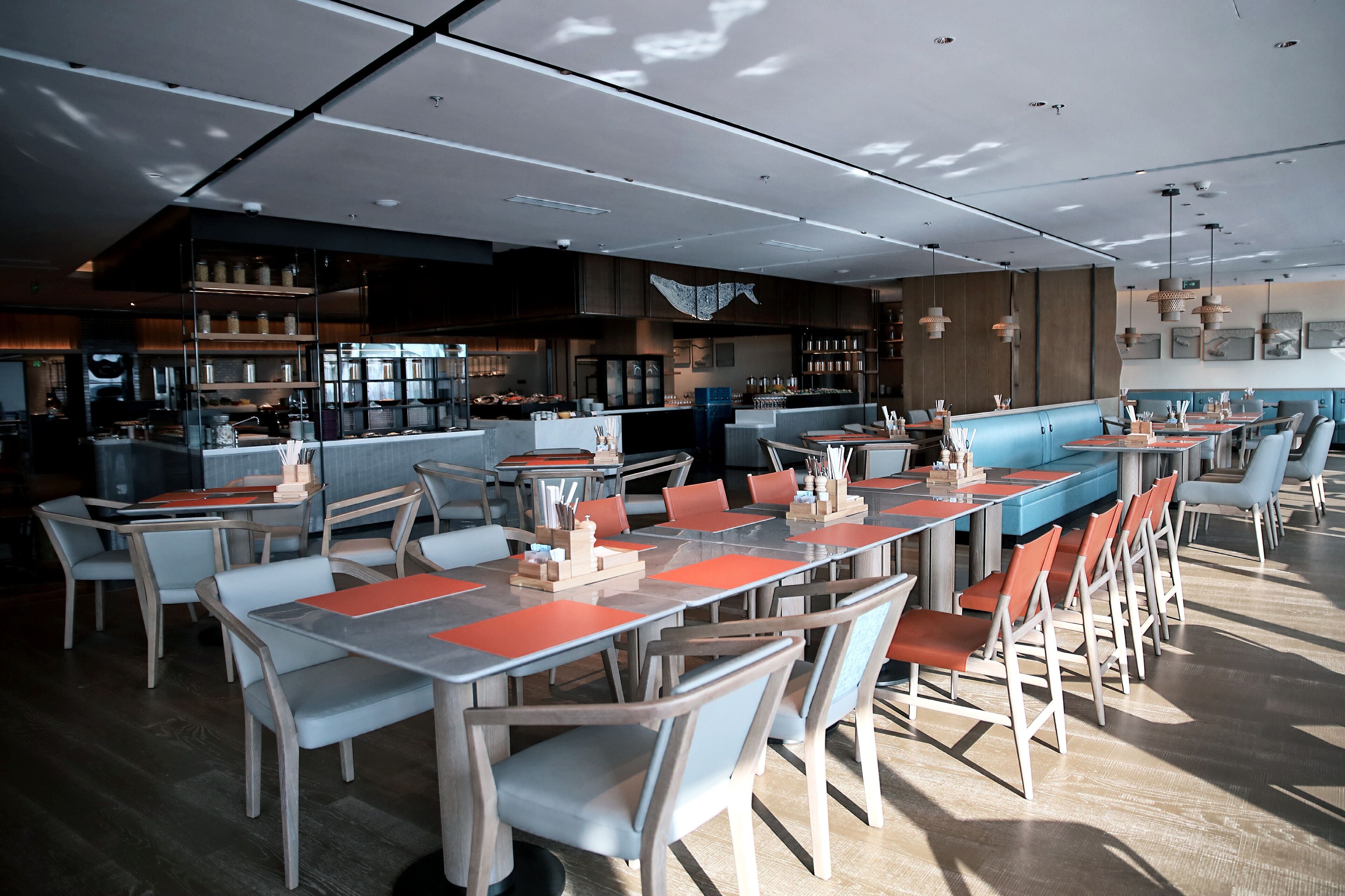 Un restaurant moderne doté de longues tables conviviales, de cabines individuelles et d’un espace bar.