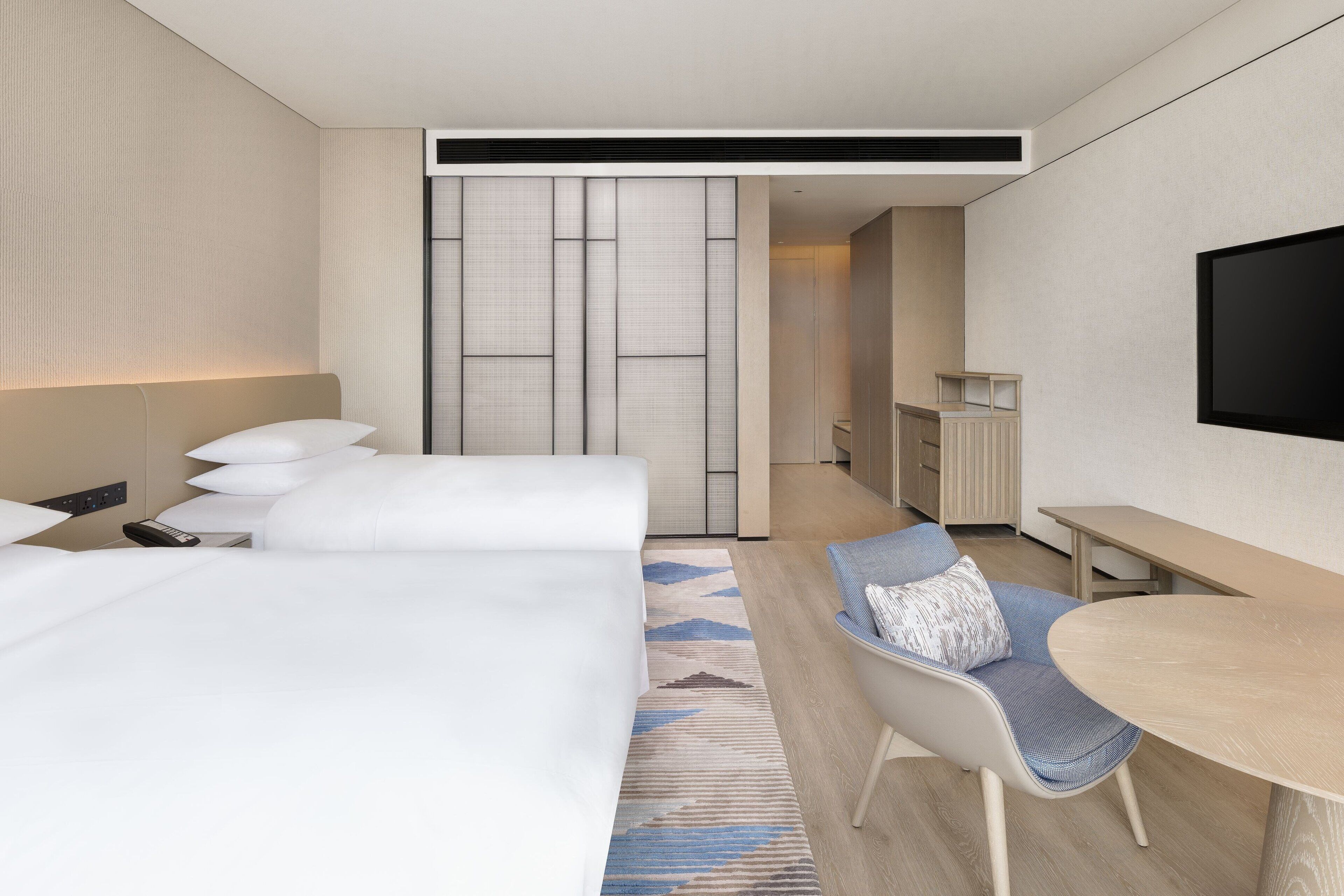 Una habitación de hotel moderna con una cama grande, un escritorio y una televisión.