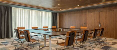 A conference room with a large table, chairs, and a patterned carpet.
