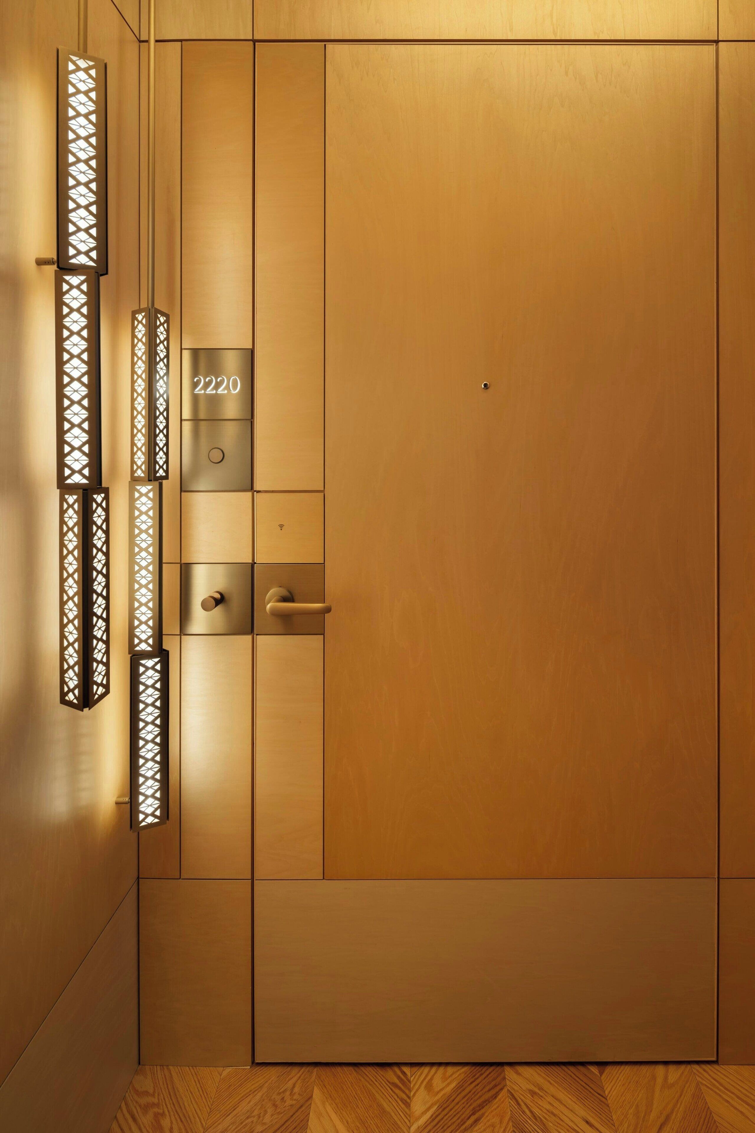 Una puerta de madera con una placa de número, un tirador y una cerradura.