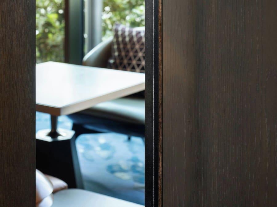 A door with a black handle and a view of an indoor seating area with a table and chairs.
