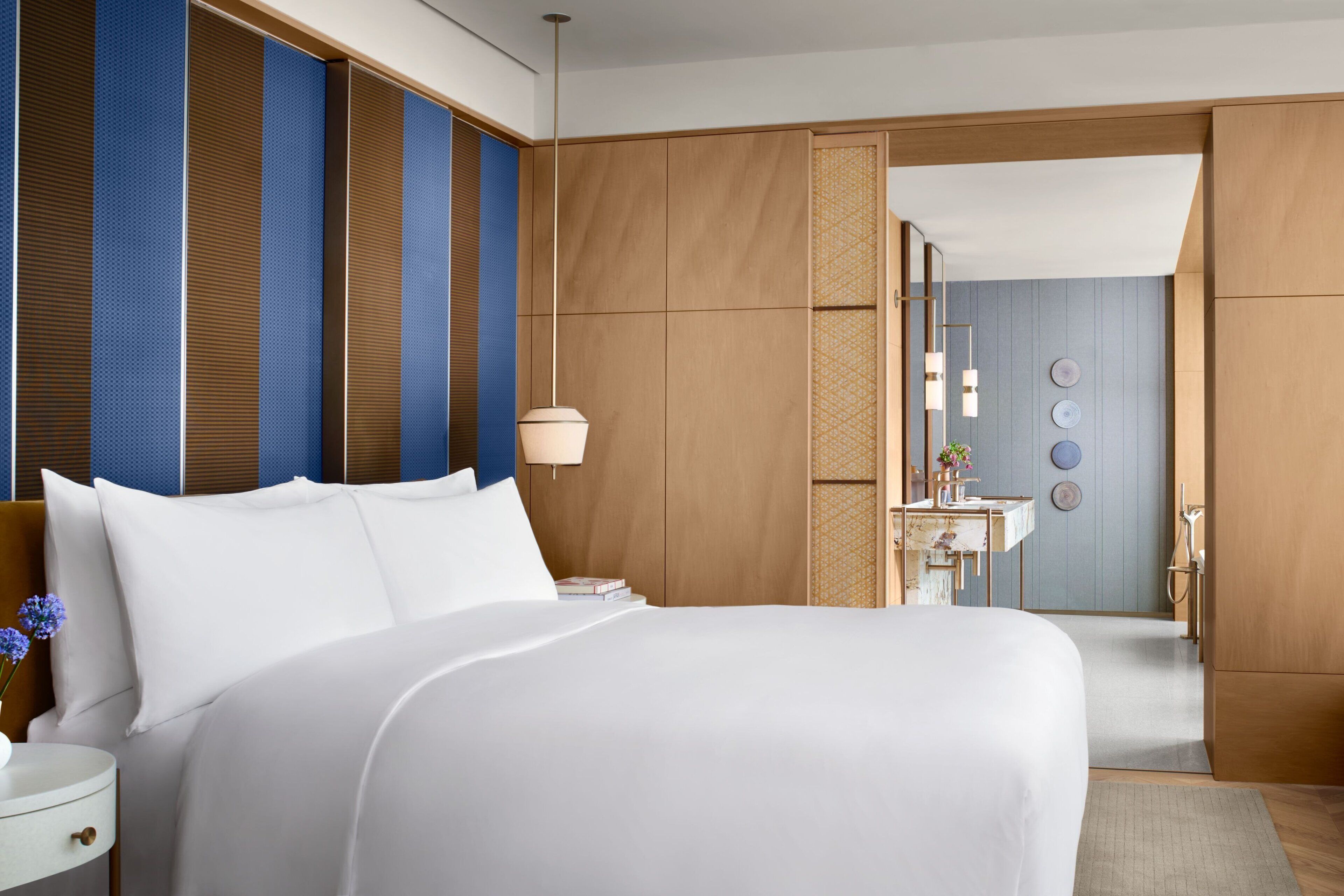 A hotel room with a large bed, a bedside table, a lamp, and a view of the bathroom.