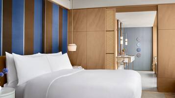 A hotel room with a large bed, a bedside table, a lamp, and a view of the bathroom.