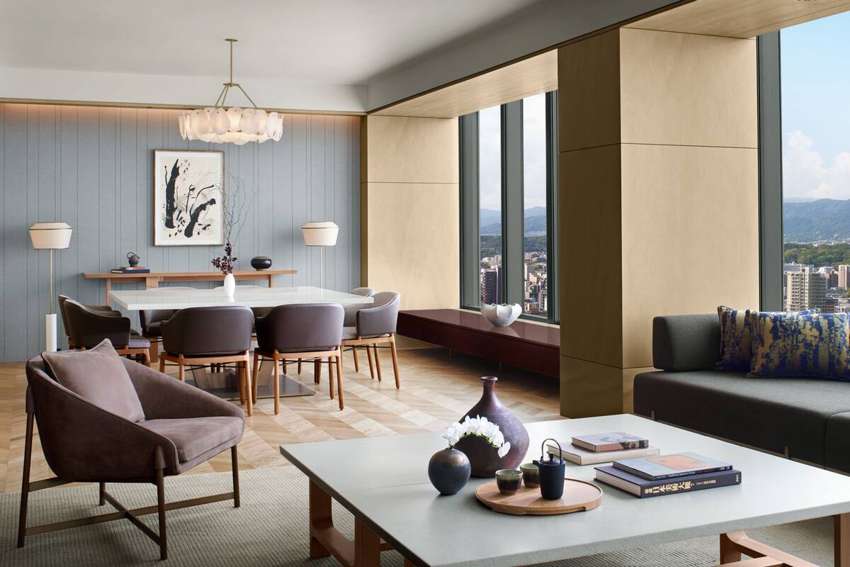 A modern living room with a dining area, large windows, and a city view.