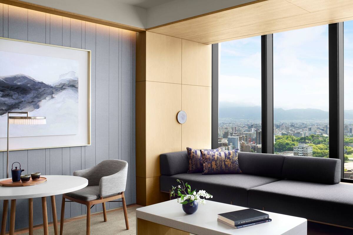 A modern room with a city view, a sofa, a table, and a chair.
