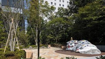 A landscaped outdoor area with a large, colorful sculpture of a dog and a tree-lined pathway.