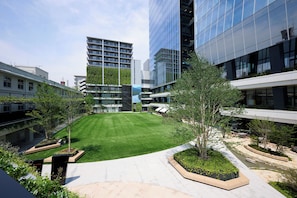 A modern building complex with a central lawn, surrounding walkways, and greenery.