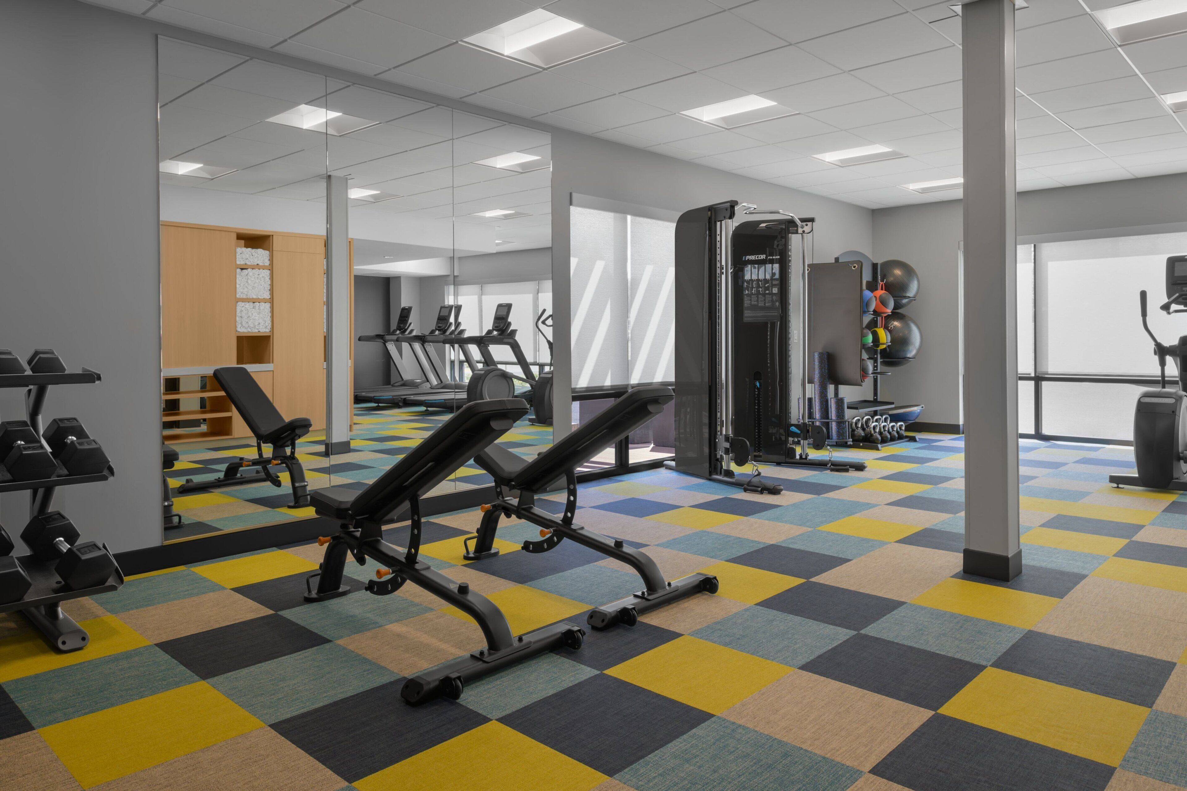 A gym with exercise equipment, a mirrored wall, and a checkered floor.