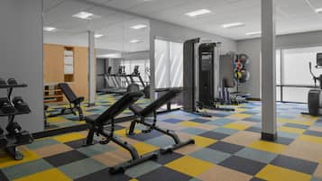 A gym with exercise equipment, a mirrored wall, and a checkered floor.