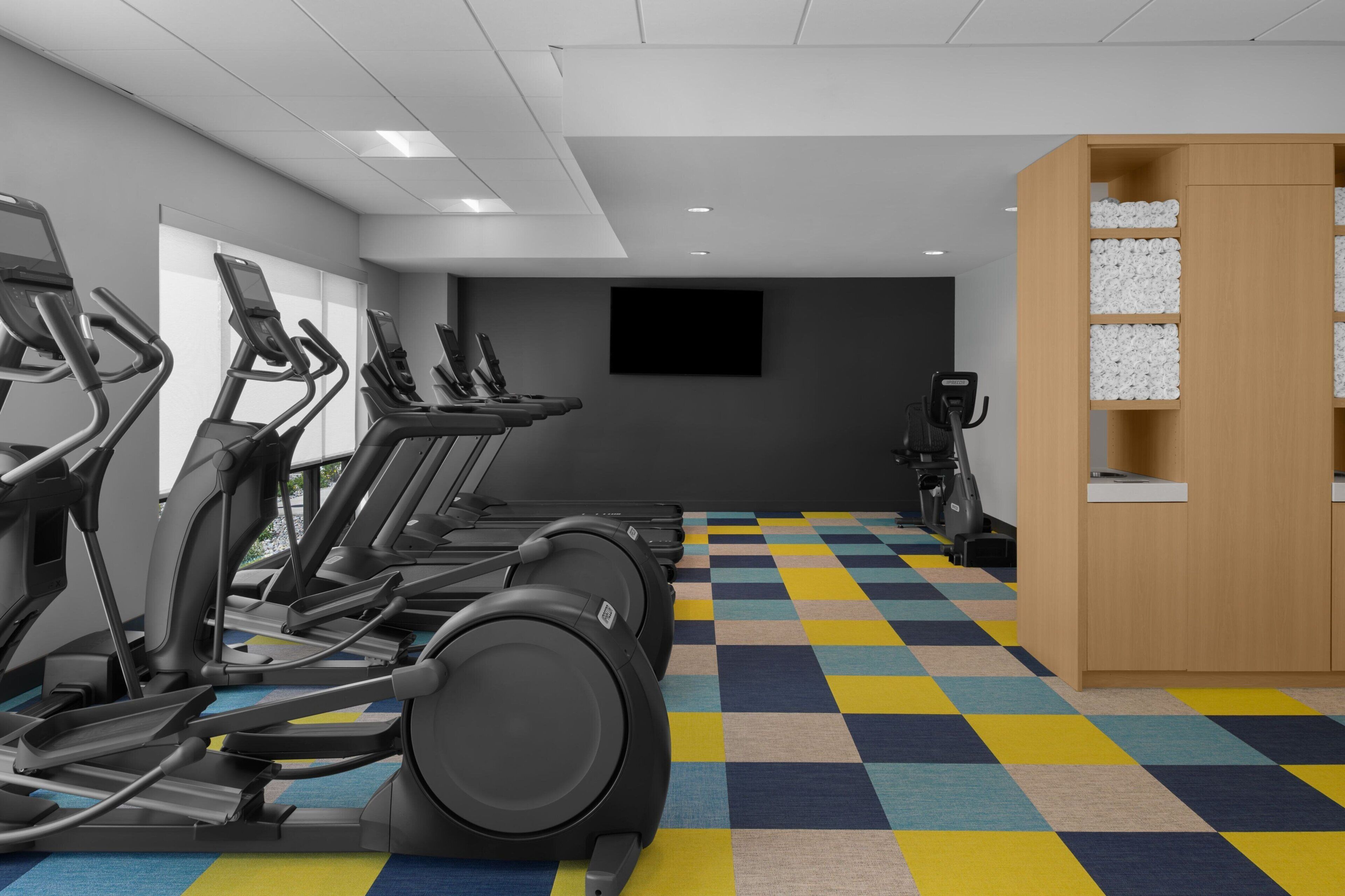 A gym with multiple treadmills, a stationary bike, and a wall-mounted TV.