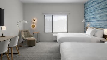 A hotel room with a bed, a desk, a chair, a TV, and a window with a view.