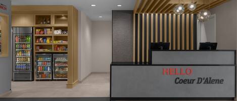 A reception area with a modern design, including a reception desk labeled "HELLO Coeur D'Alene" and a snack bar with various food items.